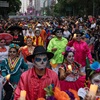 Thousands of figures in skeletal face paint march with candles in a Day of the Dead parade.