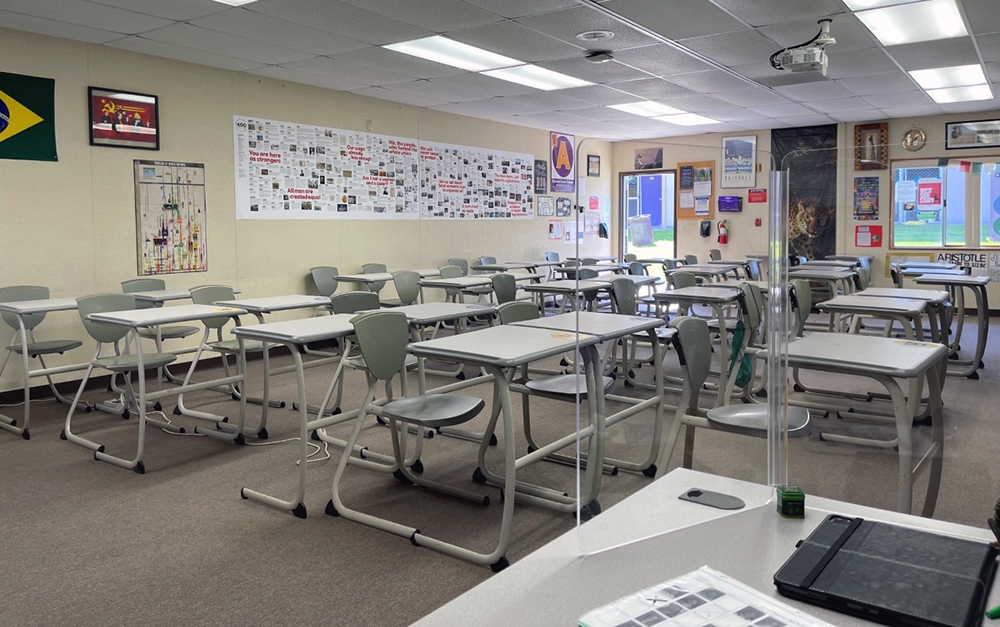 Empty classroom divided by plexiglass shields.