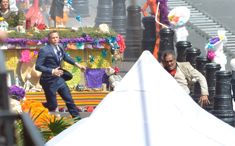 Daniel Craig as James Bond sprints through a Day of the Dead-theme parade.